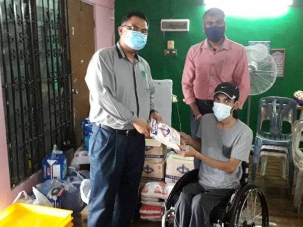 Mas Imran (kiri) menyampaikan sumbangan bahan-bahan membuat biskut dan burger kepada Mohamad Sufian di rumahnya di Taman Bahagia, Johor Bahru hari ini.