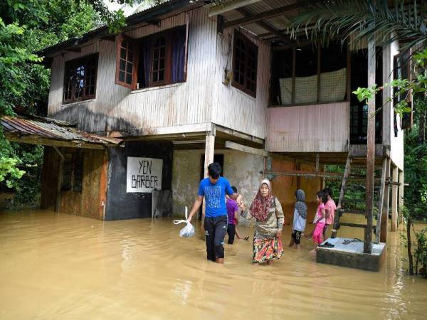 Rokiah (dua, kiri) yang ditemani cucunya Aiman keluar dari rumah untuk ke rumah anaknya setelah rumahnya dinaiki air awal pagi tadi berikutan hujan lebat ketika tinjauan di Kampung Bukit Nyior, Pelong hari ini. - Foto Bernama