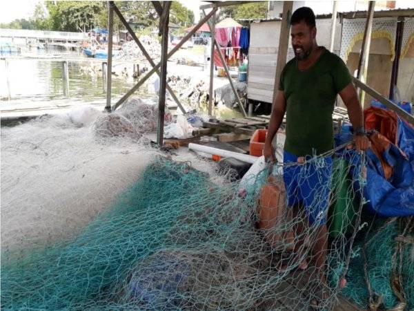Kelah membetulkan jaring sebelum dibawa ke laut untuk menangkap ikan di Kampung Orang Asli Kuala Masai, Pasir Gudang.