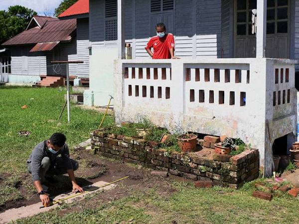 Penolong Kurator Unit Arkeologi Perbadanan Muzium Pahang Khairul Amir Abdul Karim (kiri) mengukur panjang dan lebar dipercayai batu nisan daripada zaman Dinasti Qing pada abad 17 hingga 20 yang ditemui di hadapan rumah penduduk di Kampung Pekan Lama, dekat sini hari ini.