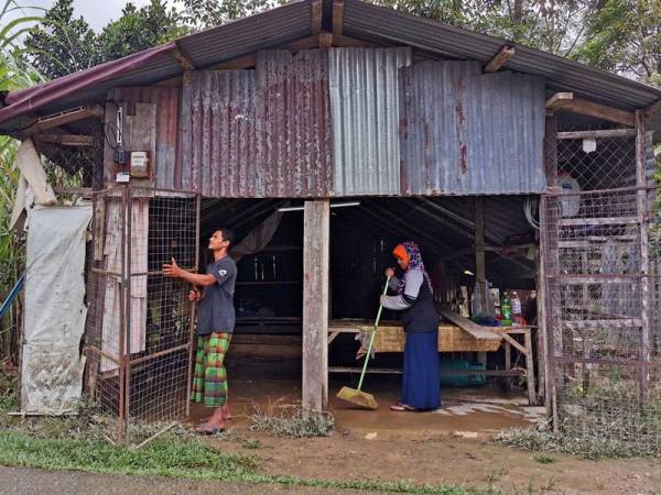 Nor Aqma dan suami, Ahmad Amir Mukminin membersihkan kediaman mereka yang dinaiki air di Kampung Bukit Nyior Pelong Setiu.