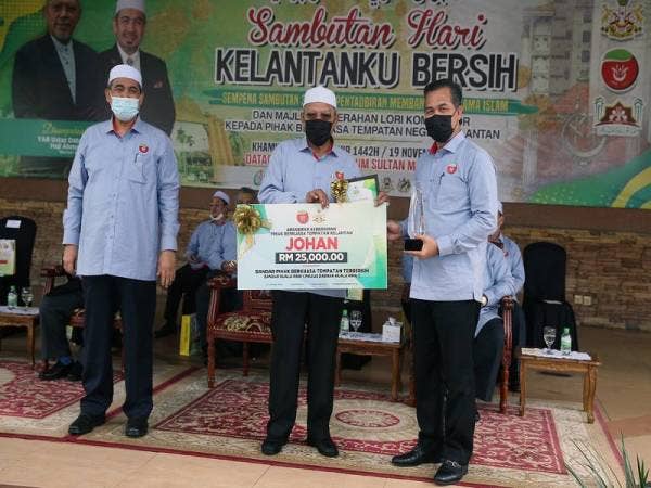 Yang Dipertua Majlis Daerah Kuala Krai, Tengku Abdul Rahman (kanan) menerima cek RM25,000 setelah Kuala Krai dinobatkan sebagai Johan bagi kategori Bandar Pihak Berkuasa Tempatan (PBT) Terbersih. 