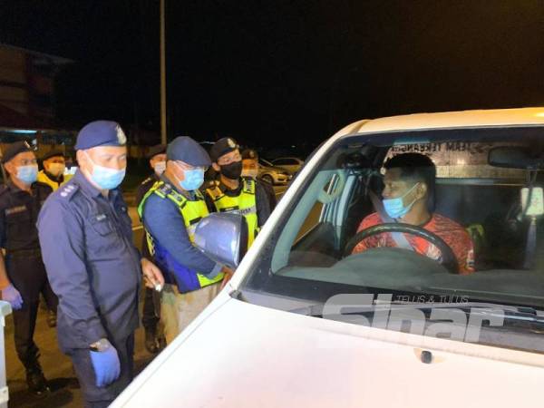 Sharfien (dua dari kiri) menyapa pengguna jalan raya di Machang semasa membuat tinjauan di sekatan jalan raya di Pulai Chondong malam tadi.