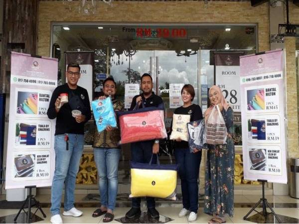 Ghazrin (dua dari kiri) menunjukkan tuala, cadar dan bantal yang dijual di pekarangan Ghazrin's Classic Hotel di Taman Dataran Larkin Johor Bahru.