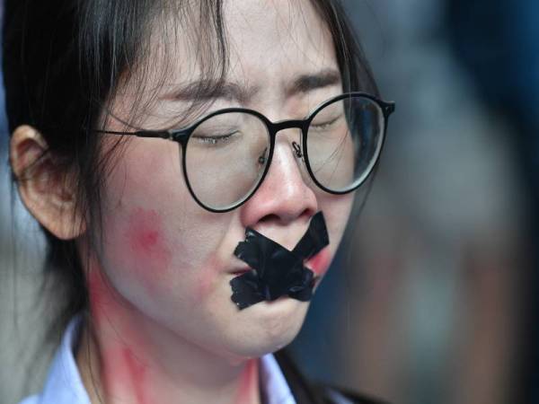 Seorang penunjuk perasaan memakai pelekat mulut ketika perhimpunan 'Pelajar Jahat' di Bangkok. - AFP c