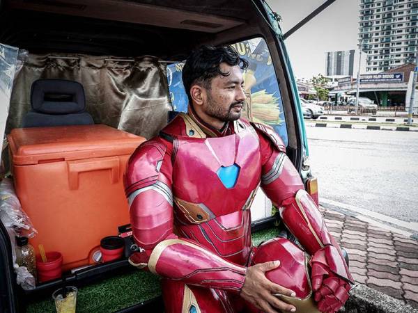 Muhammad Syukur mengambil inisiatif untuk memulakan perniagaan menjual air jagung sambil memakai kostum adiwira Iron Man selepas diberhentikan kerja akibat penularan Covid-19.- Foto Bernama