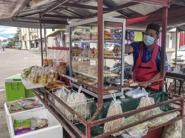 Peniaga makanan ringan, Asmawi Iberahim @ Mohd, 39, menjalankan peniagaannya seperti biasa bagi meneruskan kelangsungan hidup meskipun kehadiran pengunjung berkurangan. - Foto Bernama