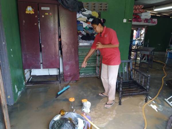 Dalina membersihkan rumahnya di Kampung Ulu Pulai selepas banjir surut pagi tadi.
