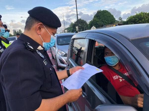 Ketua Polis Daerah Tumpat, Superintendan Ab Rashid Mat Daud (kiri) memeriksa surat kebenaran rentas daerah yang ditunjukkan seorang pengguna jalan raya ketika melalui Sekatan Jalan Raya (SJR) di sempadan daerah dari Kota Bharu memasuki ke Tumpat di Pasir Pekan hari ini.