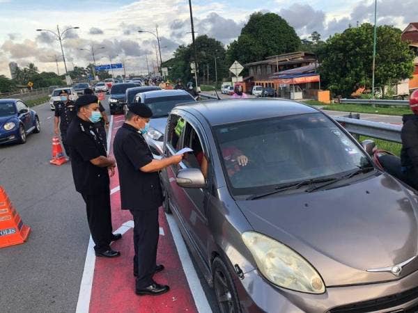 Ketua Polis Daerah Tumpat, Superintendan Ab Rashid Mat Daud (kiri) memeriksa surat kebenaran rentas daerah yang ditunjukkan seorang pengguna jalan raya ketika melalui Sekatan Jalan Raya (SJR) di sempadan daerah dari Kota Bharu memasuki ke Tumpat di Pasir Pekan hari ini.