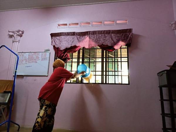 Mangsa banjir, Sharifah Sukatiau, 59, terpaksa mencedok air keluar dari kediamannya di Kampung Chepor Dalam, Chemor akibat kejadian banjir yang melanda kawasan RPT Sri Desa Chepor hari ini.