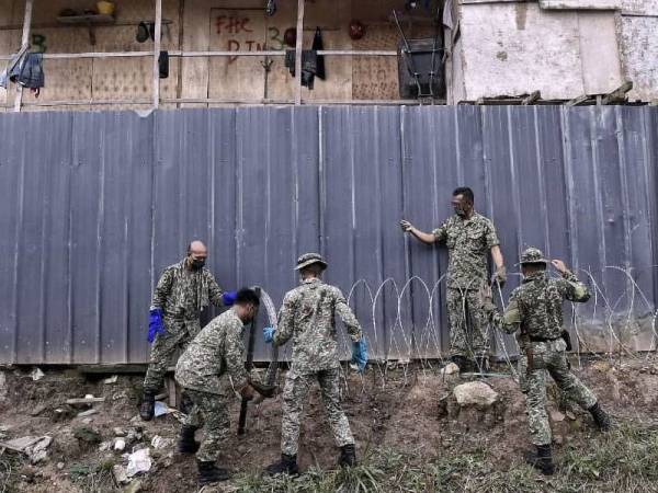 Sepasukan anggota tentera melakukan kerja pemasangan pagar kawat berduri di sekeliling rumah kongsi pekerja binaan di tapak pembinaan K-Avenue, Penampang hari ini.