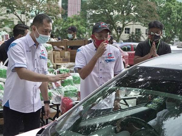 Roslan (dua dari kiri) bersama Ketua Gegar, Aizat Safii (kiri) memberikan sumbangan kepada pemandu teksi menerusi program berkenaan di ruang parkir bersebelahan Melawati Mall hari ini.