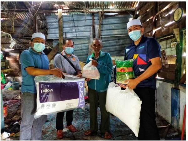 Sumbangan bantal dan bekalan makanan disampaikan kepada Long (dua dari kanan) di rumahnya di Kampung Hujung Sungai Tebengau di sini hari ini.