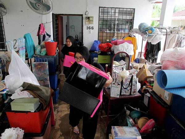  Penduduk setempat Nurhidayah Ahmad Tajri, 27, (depan) bersama adiknya Nurhusna Nabilah, 20, melakukan kerja-kerja pembersihan kediaman ibu bapanya selepas dilanda banjir semalam di Kampung Chepor Dalam, Chemor hari ini.