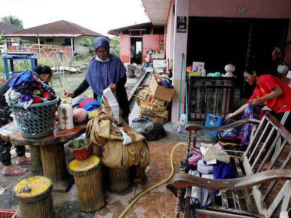 Penduduk setempat Tukiah Abu Yamin, 62, (dua,kanan) dan anak-anaknya membersihkan pakaian dan langsir selepas kediamannya dilanda banjir semalam di Kampung Chepor Dalam, Chemor hari ini.