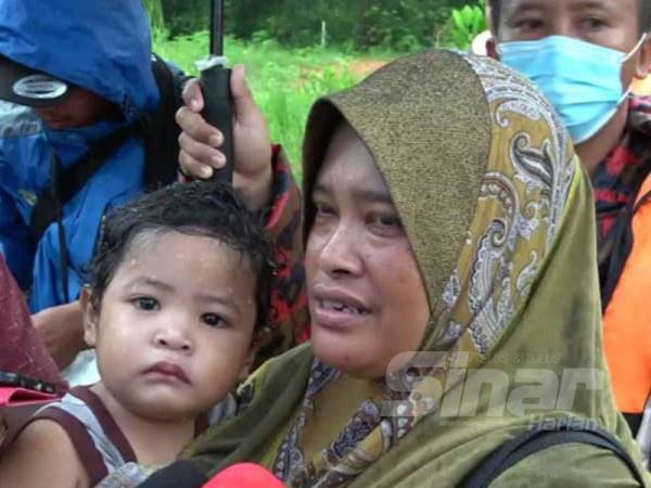 Suriati (kanan) bersama anaknya, Adeeb yang berjaya diselamatkan anggota bomba selepas terjatuh ke dalam banjir di rumahnya di Kampung Petaling, Kuala Nerus hari ini.