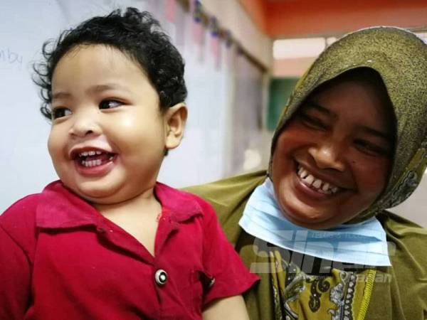 Suriati (kanan) bersama anaknya, Adeeb yang berjaya diselamatkan anggota bomba selepas terjatuh ke dalam banjir di rumahnya di Kampung Petaling, Kuala Nerus hari ini.