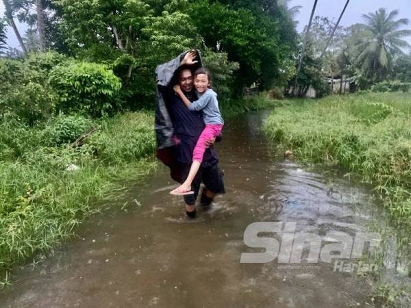 Md Zulfaisal terpaksa mendukung anaknya, Nur Qurratu Izara ketika keluar dari rumahnya kerana air kotor dan busuk.