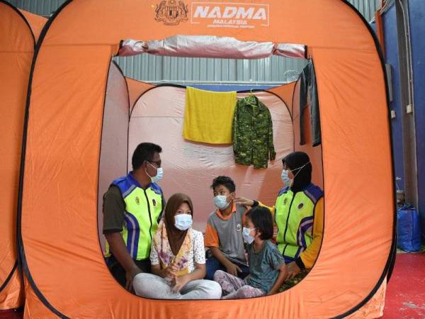 Anggota Jabatan Sukarelawan Malaysia (RELA), Erawati Jaafar (kanan) bersama suami Roslan Hassan (kiri) dan anak-anak mereka Ahmad Razin Riffat, 12, Atikazahra Latifa, 9, dan Atika Alia Amani, 6, ketika ditemui di pusat pemindahan sementara (PPS) Dewan Sivik Kampung Air Putih hari ini. - Bernaama