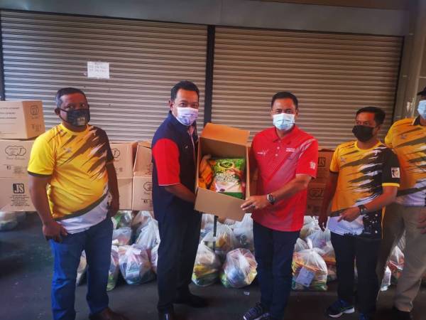 Mohd Rosli (kiri) menyampaikan bantuan bakul makanan kepada Yakub (kanan) sebelum diserahkan kepada penduduk di bawah DUN Karambunai, di Sepanggar, Kota Kinabalu.