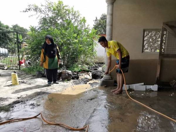 Azman membantu ibunya, Aishah membersihkan kediaman mereka yang dinaiki air di Felda Seberang Tayor, Kemaman.