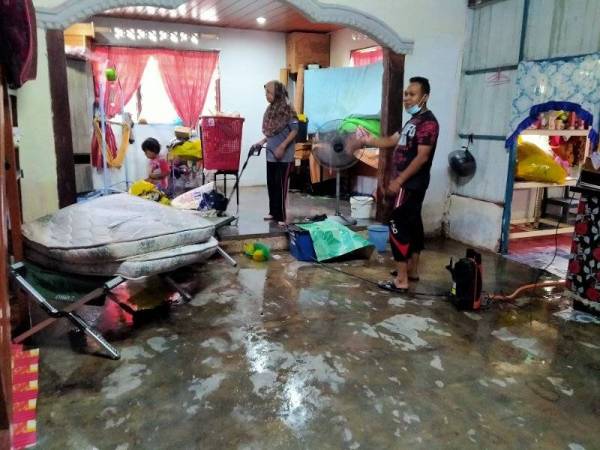 Mohd Khir dan keluarga sedang membersihkan rumah yang dilanda banjir kilat semalam.