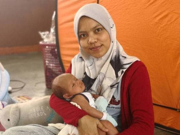 Ain Nur meriba anak bongsunya semasa ditempatkan di PPS SK Dato Maharajalela sejak lima hari lalu.