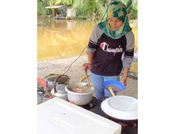 Halima Tu'saadiyah memasak di bawah khemah selepas banjir melimpah masuk ke rumah.