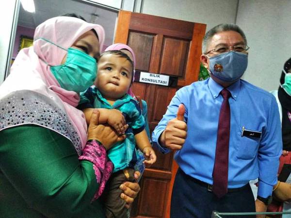Dr Adham bersama Rusnaini dan anaknya, Hazim yang menjadi bayi pertama menerima suntikan tersebut di KKIA Raub hari ini.