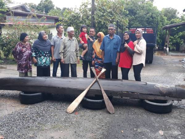Mat Isa (empat dari kiri) bersama ahli keluarganya bergambar kenangan dengan perahu sagor miliknya sebelum dipindahkan ke dalam lori untuk dibawa ke Universiti Utara Malaysia (UUM) semalam.