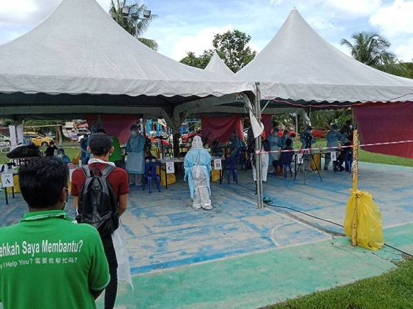 Penduduk sedang menjalani saringan di pekarangan Dewan Masyarakat Taman Meru di sini hari ini.