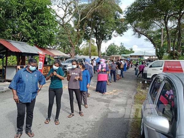 Penduduk beratur sebelum masuk Dewan Masyarakat Taman Meru di Klang untuk melakukan saringan Covid-19 hari ini.