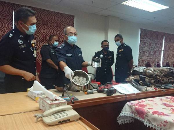 Shahrul Lalli menunjukkan serpihan yang terdapat dalam tabung ekzos sebelum diproses menjadi emas putih ketika sidang media di Ibu Pejabat Kontinjen Polis (IPK) Melaka di Bukit Beruang di sini, hari ini.