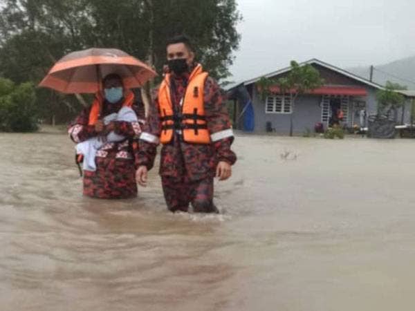 Anggota bomba mendukung bayi lelaki Siti Nur Hazrin Najwa yang berusia 10 hari di Kampung Padang Kemunting, Kuala Nerus hari ini..