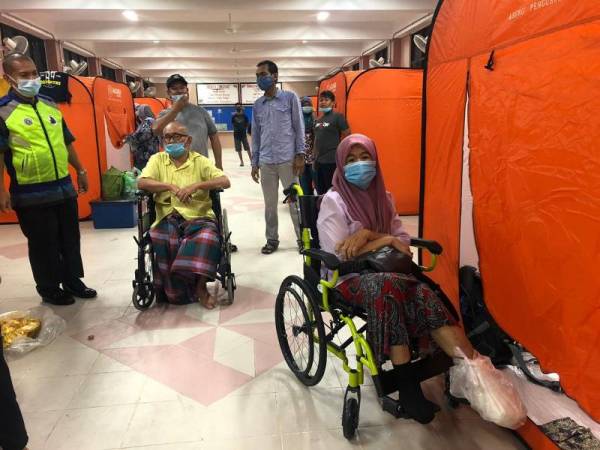 Nik Hassan (dua dari kiri) yang kudung kaki kanan separas paha manakala seorang lagi mangsa,
Aini yang kudung empat jari kaki kiri (kanan) ditempatkan di PPS SK Tiong bersama 50 mangsa banjir dari Kampung Tiong dan Kampung Rupek, Kota Bharu.