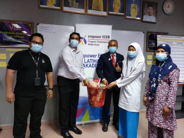 Mohd Nazron (dua dari kiri) menyampaikan sumbangan kepada salah seorang pelajar cemerlang.