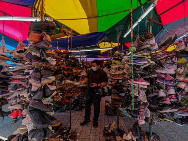 Seorang pelanggan dilihat sedang memilih kasut terpakai di deretan gerai menjual pakaian dan aksesori bundle di Lorong Haji Taib, Chow Kit ketika tinjauan di ibu kota hari ini.