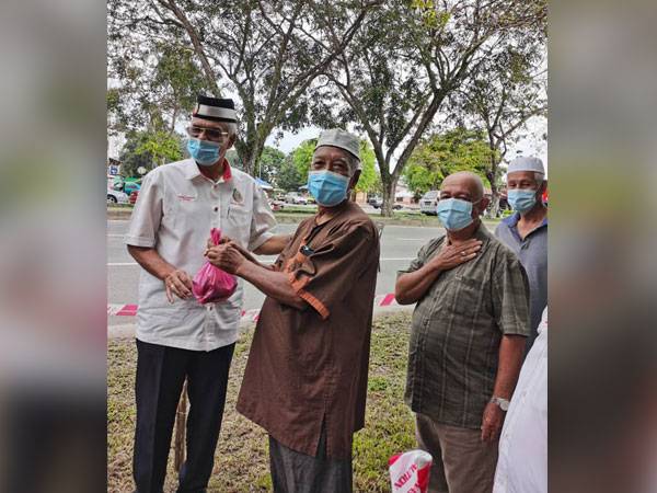 Ahmad (kiri) menyerahkan ikan percuma kepada penduduk setempat pada Program Pemberian Ikan Mentah kepada penduduk sekitar Kota Setar di depan Medan Selera Taman Wira Mergong, Alor Setar hari ini.