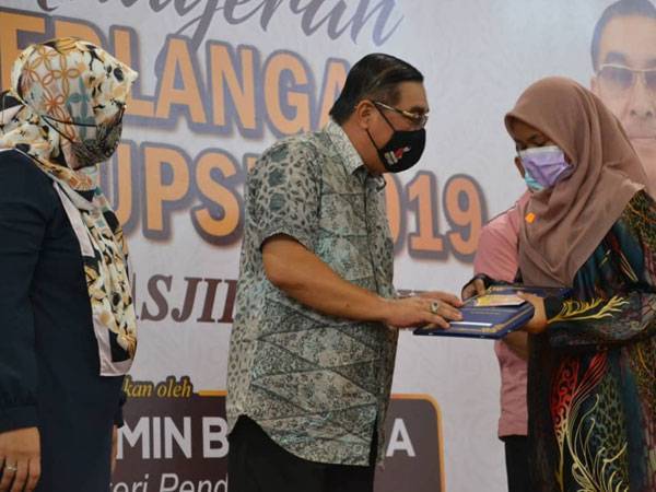 Muslimin (tengah) ketika menyampaikan anugerah pelajar cemerlang kepada salah seorang pelajar terpilih di Kompleks Sukan Masjid Tanah hari ini.