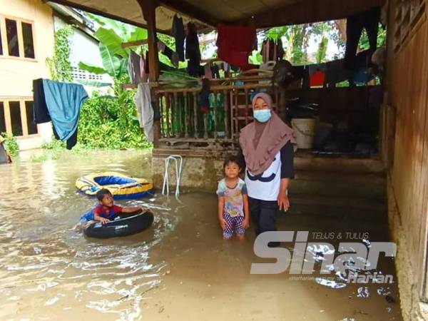 Alani bersama anaknya sudah bersedia untuk berpindah selepas kawasan rumahnya di Pekan Rantau Panjang mula ditenggelami banjir sejak malam tadi.