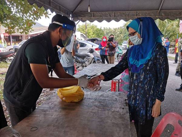 Pegawai kesihatan memotong gelang yang dipakai penduduk sejurus tamat PKPD.