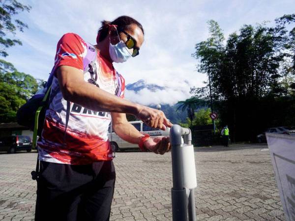 Aten Yukem, 37, dari Sandakan menggunakan pembasmi kuman sebelum melakukan pendakian Gunung Kinabalu. - Foto Bernama