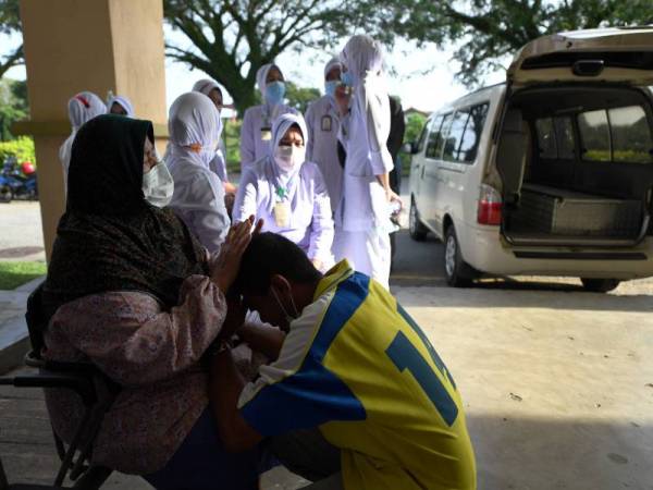Suasana pilu menyelubungi sekitar Unit Forensik Hospital Pekan semalam. Kelihatan Asmawi Yusoff, 45, dan mentuanya Rahimah Abdullah, 65, tidak dapat menahan kesedihan ketika menunggu jenazah isterinya, jururawat Julayha Kudus, 39. - Foto Bernama