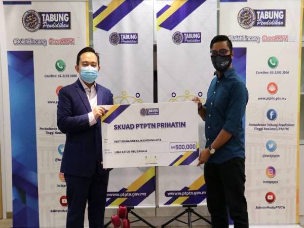 Wan Saiful (kiri) menyerahkan replika cek kepada Mohd Fadli semasa Majlis Penyerahan Sumbangan Skuad PTPTN Prihatin kepada DANA KITA yang disiarkan di Facebook rasmi PTPTN semalam.