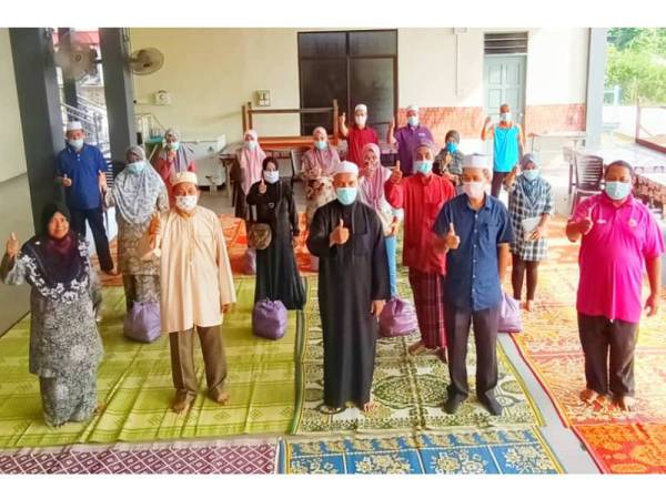 Ismail (hadapan, tengah) dan AJK Masjid Al-Hanan Simpang Empat Tendong, Pasir Mas bersama penerima bantuan Covid-19.