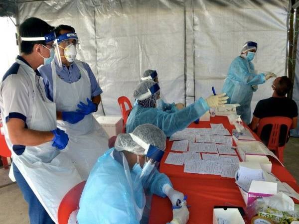 Dr Azlan (dua dari kiri) meninjau petugas kesihatan melakukan ujian saringan Covid-19 terhadap pekerja kilang warga asing kumpulan syarikat Kossan di Meru hari ini. Foto Bernama