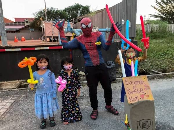 Mohd Shahril memakai kostum 'Spiderman' menghiburkan kanak-kanak semasa menjual belon pelbagai bentuk dengan bayaran seikhlas hati. - Foto Bernama