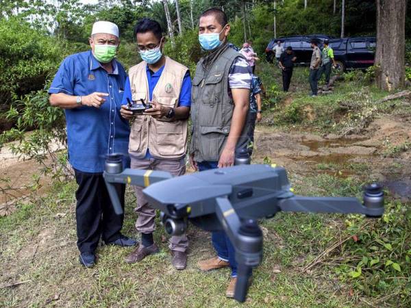 Pengarah Jabatan Perhutanan Kelantan, Abdul Khalim Abu Samah (kiri) melihat anggotanya dari unit dron Mohd Shahril Yusop (tengah) menerbangkan dron bagi memantau aktiviti pencerobohan hutan di Hutan Simpan Kekal (HSK) Chabang Tongkat, hari ini. - Bernama
