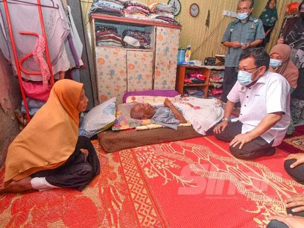 Che Abdullah (kanan) bertanya khabar kepada Mek Nab Ismail, 74, (kiri) mengenai suaminya Ariffin Dotan, 78, yang lumpuh sempena Program Ziarah Peladang di Kampung Kok Pasir hari ini.